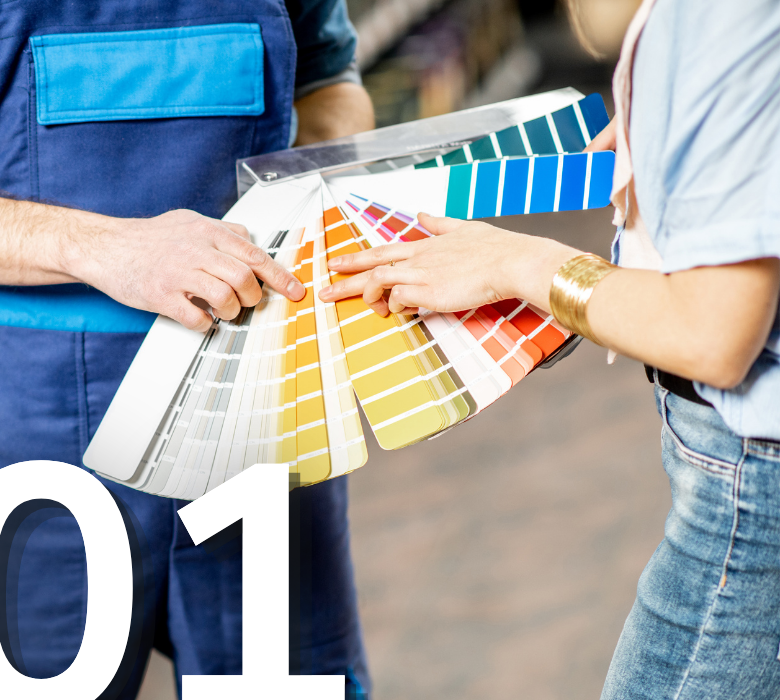 A store employee showing a customer a large, fanned-out deck of paint color swatches in various shades