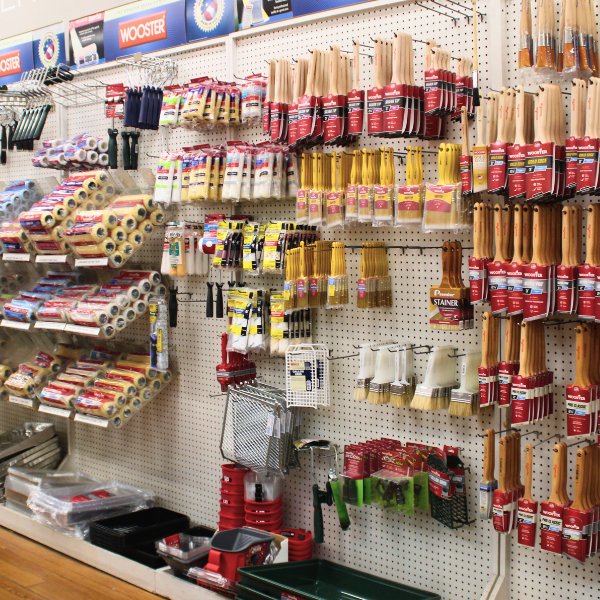 A display wall at Lebanon Paint & Wallpaper fully stocked with paintbrushes, Wooster brushes, rollers, and paint trays