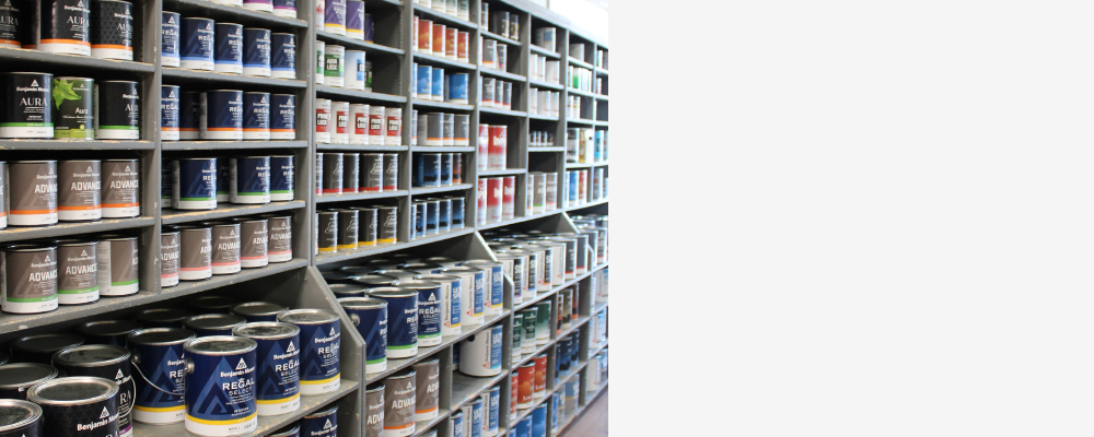 Shelves stocked with a variety of Benjamin Moore paint cans, featuring lines like Aura, Regal Select, and Advance