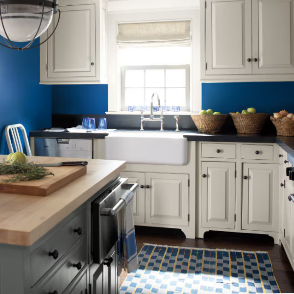 Sunlit kitchen with bold Williamsburg Collection blue walls and white cabinets by Benjamin Moore, available at Lebanon Paint & Wallpaper